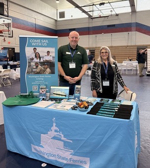 Washington State Ferries recruitment booth with two representatives in a gymnasium setting.