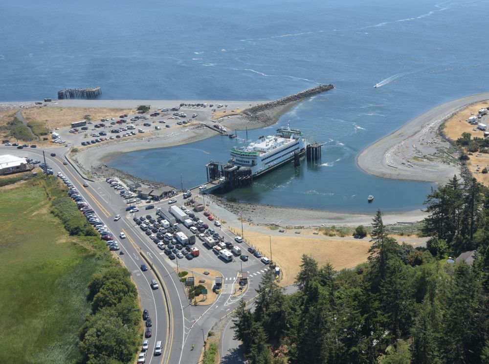 Aerial view of Coupeville terminal at Keystone Harbor with a docked ferry, vehicle holding lanes, parking lots and surrounding beaches.