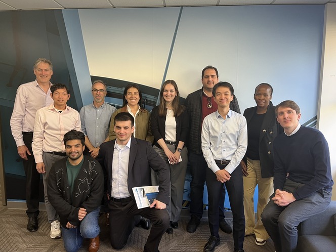Eleven people posing for a photo in an office setting.