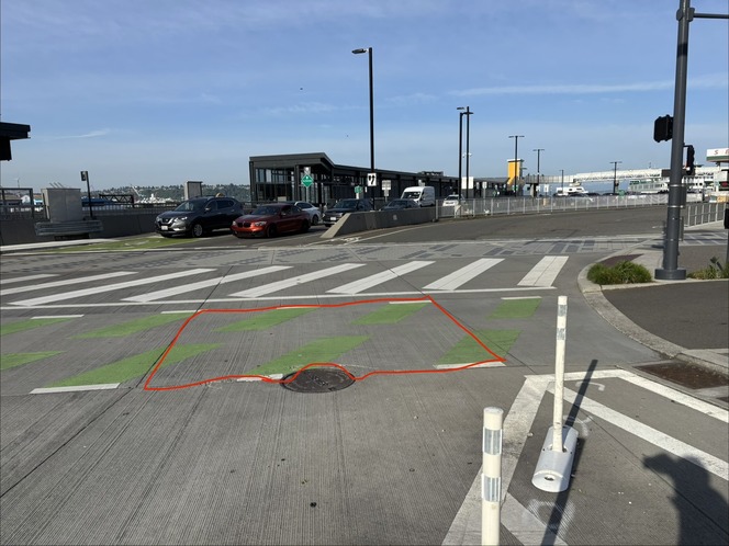 A street scene with a crosswalk, a bike lane, and vehicles, and an area on the concrete pavement outlined with a red box.