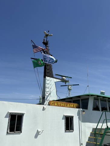 The upper structure of a ferry named "CATHLAMET" with a U.S., Washington state and 75 flag on a mast.