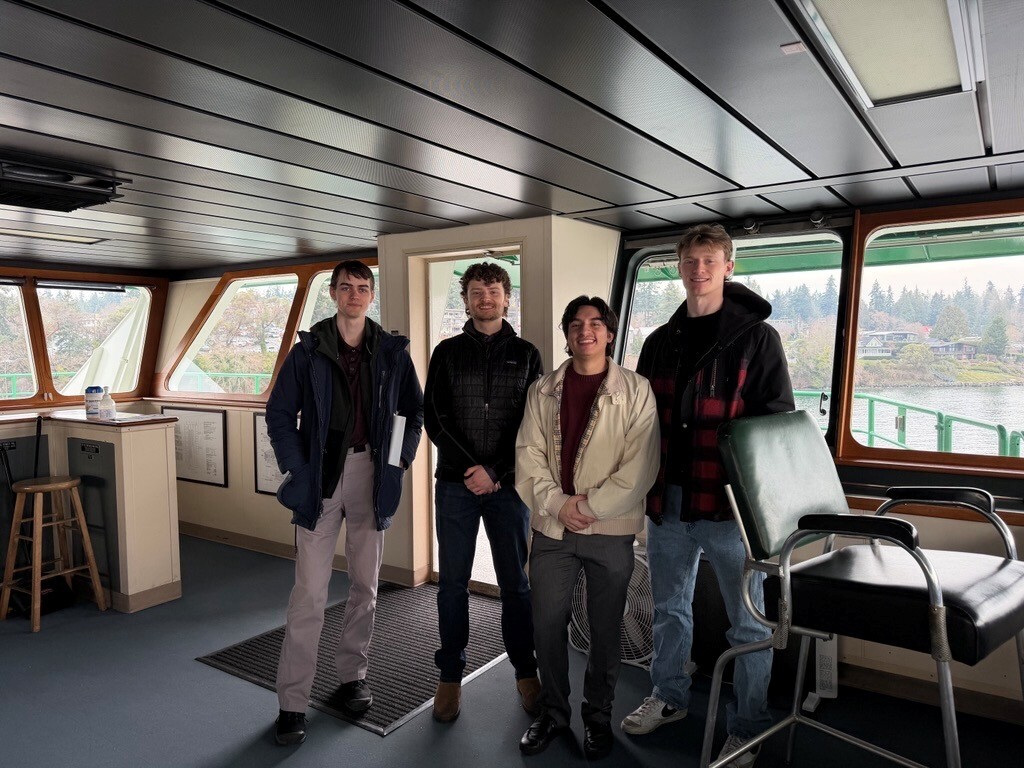 Four people in a ferry's pilothouse.