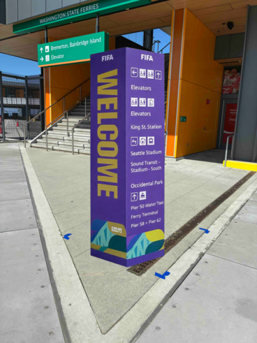 Tall purple welcome sign with directions near an entrance to Washington State Ferries.