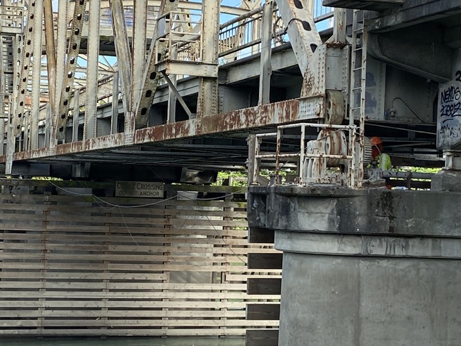 A crew member works under the State Rout 536 Skagit River Bridge to install rigging wires for a containment system.