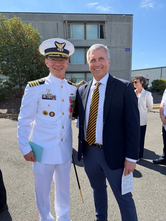 A person in a white military uniform with medals on the left and person in right in a dark suit with a striped tie.