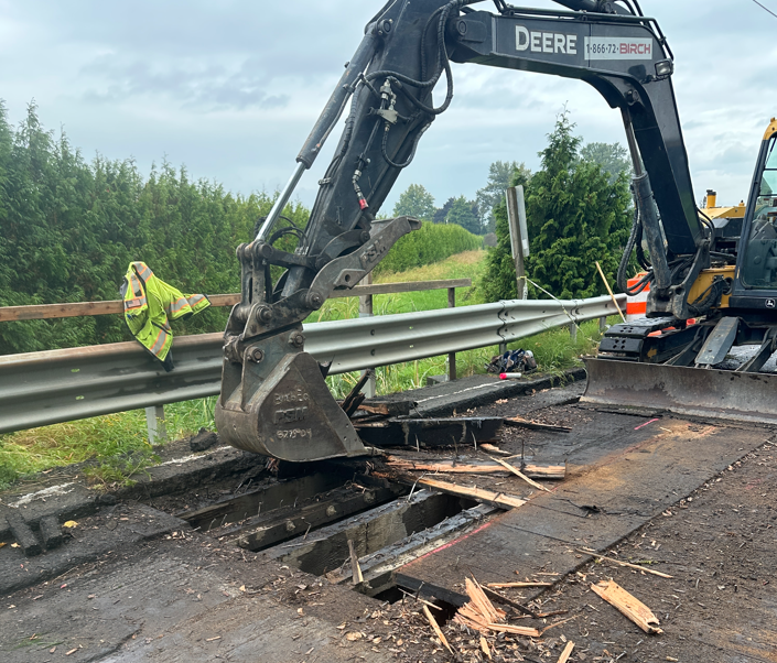 Construction work site on SR 9 with an excavator removing timber decking from the Klein Ditch Bridge.