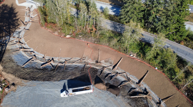 Aerial photograph showing hillside construction in a forested valley beside I-5. 