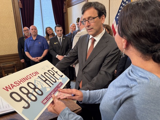 Gov. Ferguson is shown the 988 Suicide Prevention Lifeline license plate emblems. 