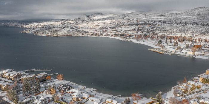 Aerial view of Lake Chelan in winter. Snow is on the ground and larch trees line the shoreline.