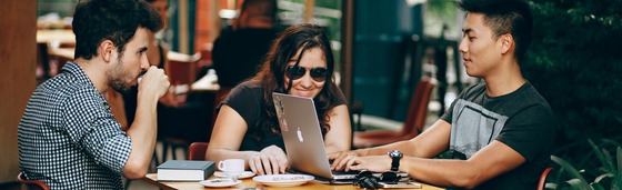 three students sitting at table looking at laptops by Helena Lopes on Unsplash