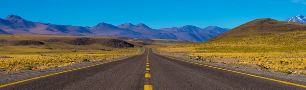 paved road with mountains in background. photo by Danel Cartin on unsplash