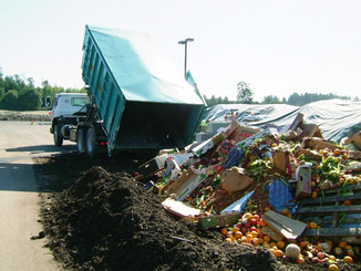 A truck unloads food and yard waste at a compost facility.