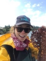 A woman smiles at the camera while holding seaweed
