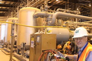 A person in a hard hat standing in front of industrial waste treatment equipment