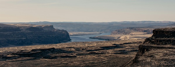View of rocky plateau with Columbia river flowing through it and blue sky 