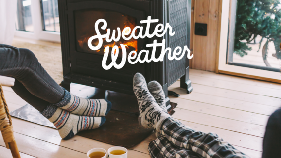 Two people with wool socks sitting by a fire with hot tea, text says sweater weather