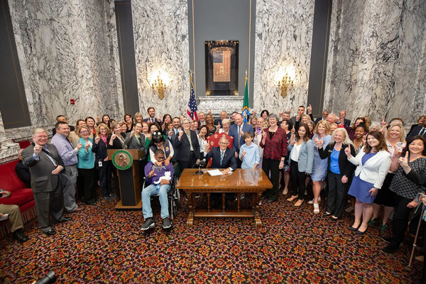 Gov. Jay Inslee and a crowd gather for the signing of the first public option into law in 2019