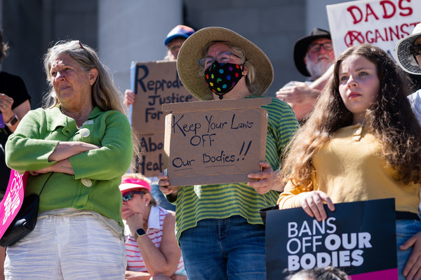 A woman attending a rally holds a sign reading, ?Keep Your Laws OFF Our Bodies"