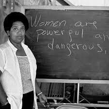 Photo of Black Woman standing at a chalkboard