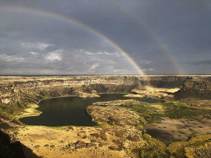 Lakes surrounded by cliffs, with two rainbows overhead