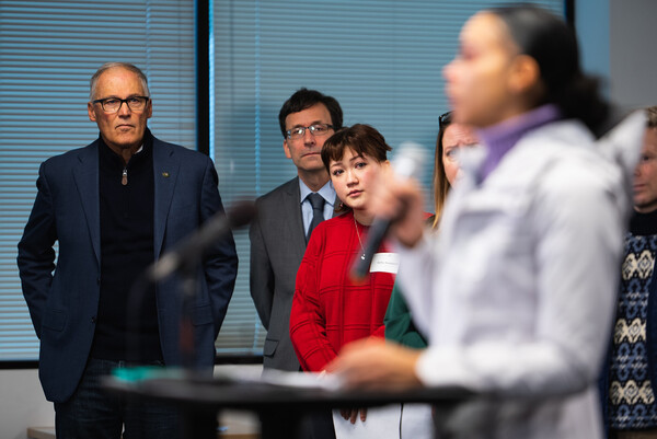 Gov. Jay Inslee and Attorney General Bob Ferguson listen to the wife of a victim of gun violence.