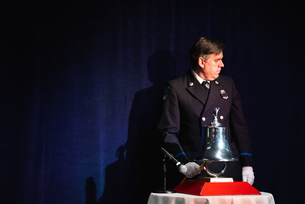 A firefighter tolls a bell for each name read from a roster of workers killed on the job.