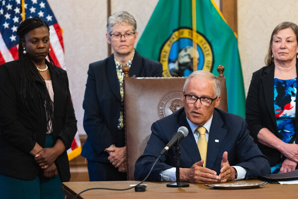 Gov. Jay Inslee signs SB 5536 flanked by lawmakers.