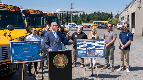 Gov. Jay Inslee speaks at a press conference in front of electric buses.