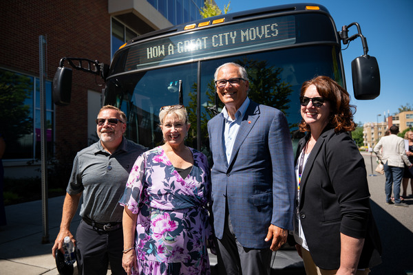 Gov. Jay Inslee and Spokane officials pose in front of a new electric bus.