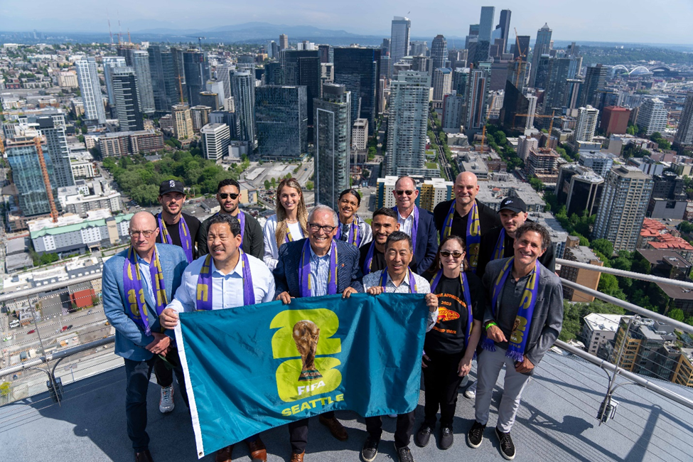 Gov. Jay Inslee holds up the 2026 FIFA World Cup flag to celebrate Seattle?s selection as a host city.