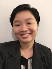 Vic is smiling and looking at the camera. Vic, an Asian person, has short hair, and is wearing dark gray clothing against a white background.