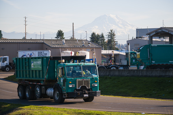 A garbage truck passes by with Mount Rainier in the background.