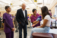 Students take blood pressure readings in a health care education class as Gov. Jay Inslee watches on.