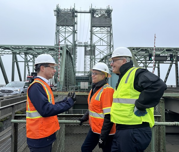 U.S. Secretary of Transportation Pete Buttigieg chats with Oregon Gov. Tina Kotek and Washington Gov. Jay Inslee on a bridge.