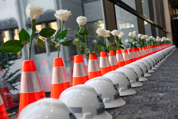 A line of helmets and flowers honors fallen WSDOT workers.