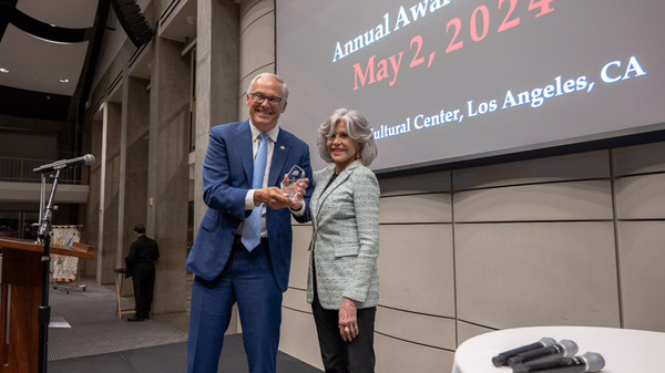 Actress Jane Fonda presented Inslee with an award onstage in a conference hall.