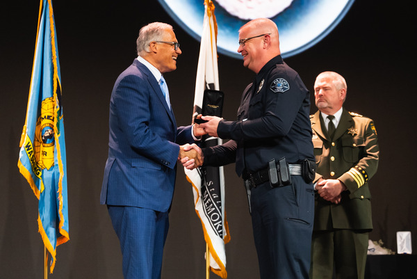 Gov. Jay Inslee presents a police officer a medal