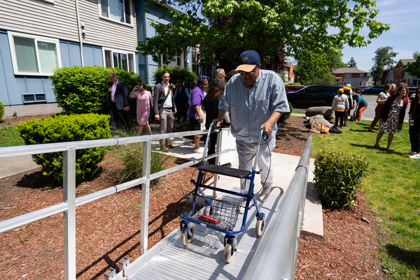 A man walks up an accessible ramp to his home using a walker.