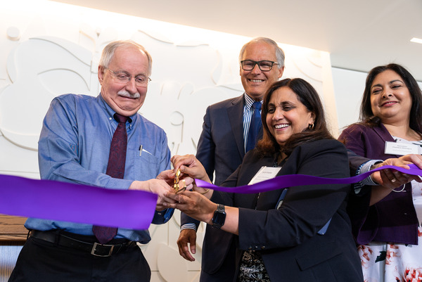 A group of people help cut a ribbon to open a new facility.