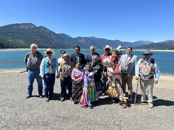 A group of people standing on a rocky shore in front of a lake