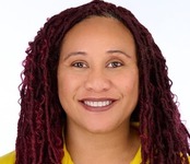 Evelyn Tuiaana, a Pacific Islander adult with tan skin and long, dark reddish braided hair, wearing a bright yellow polo shirt