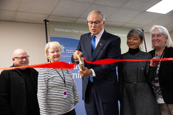 Gov. Jay Inslee cuts a ribbon, surrounded by legislators