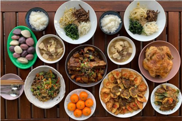 Plates and bowls filled with international foods on a wooden table