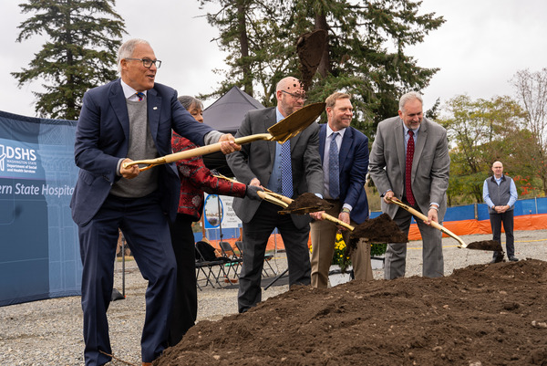 Group of people shoveling dirt for a groundbreaking ceremony