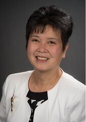 Lorraine Lee wearing a white jacket over a black blouse. 