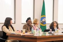 Teddy Kemirembe smiling with three other women seated at a table.