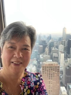 Lorraine Lee standing by a window overlooking a big city skyline