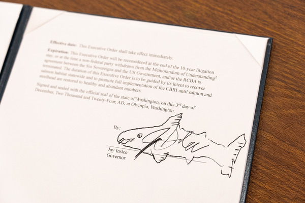 A document signed by Gov. Jay Inslee with his signature bordered by an illustration of a fish.