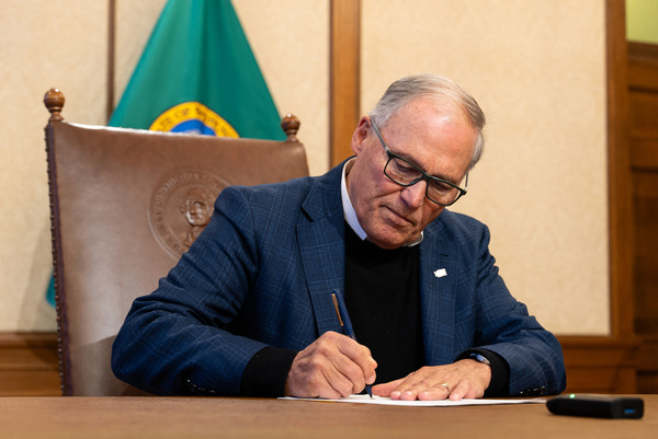 Gov. Jay Inslee signs a document.