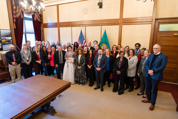 A large crowd of people smiles for a photo in a conference room.